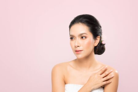 Beautiful Young Woman with clean fresh skin, Proposing a product. Gestures for advertisement on beige backgroundの写真素材