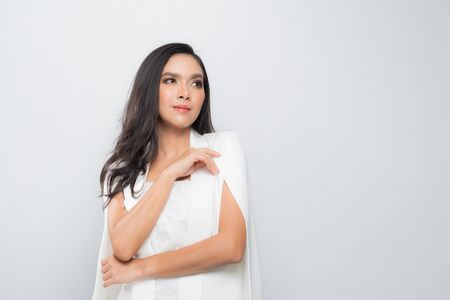 High fashion shoot of young black hair woman wearing a white suit female in white suit isolated on gray background.の写真素材