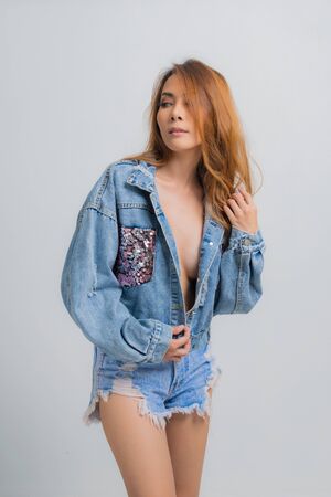 Beautiful asian woman in a sexy denim shirt fashion on isolated gray background.の写真素材