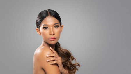 Beautiful black woman with clean fresh skin, Proposing a product. Gestures for advertisement isolated on gray backgroundの写真素材