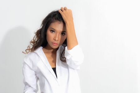 Beautiful asian woman with perfect skin and wearing a white shirt in profile isolated on gray background.の写真素材