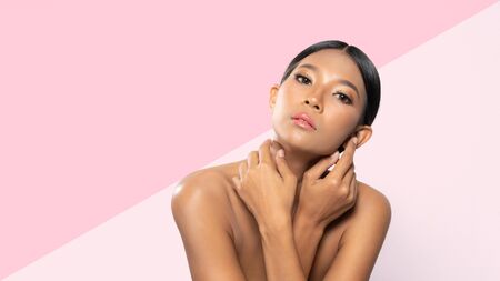 Beauty black woman with clean fresh skin, proposing a product gestures for advertisement isolated on pink two tone backgroundの写真素材