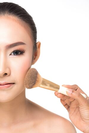 Beautiful Young Woman with clean fresh skin, Proposing a product. Half face with Makeup brush Gestures for advertisement on white backgroundの写真素材