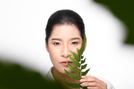 Beautiful asian young woman holding green plant on white background.の写真素材