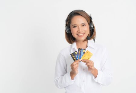 Friendly female helpline operator or call center showing blank credit card, headset holding her arms crossed isolated on white background.の写真素材