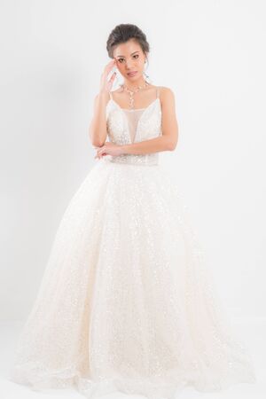 Beautiful bride portrait wearing a white wedding dress with a luxury at studio shoot isolated on white background.の写真素材