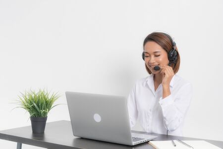 Close-up portrait of a woman call center and customer service agent sitting at her workplace and chatting online. Isolated on white background.の写真素材