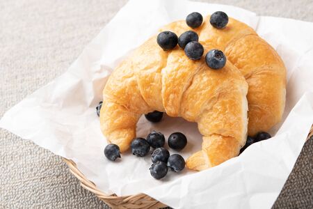Croissants with fresh blueberries in basket is delicious pastry on the table.の写真素材