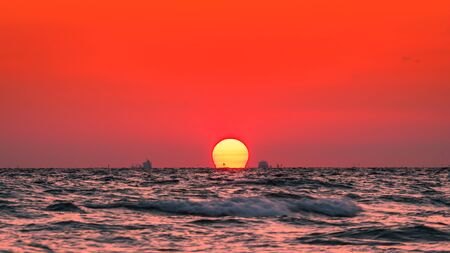 Beautiful big sunset over sea on orange sky background evening time.の写真素材