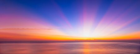 Beautiful background sunrise or sunrise sky with sunbeam over the sea. Copy space and banner composition.の写真素材