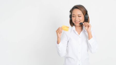 Friendly female helpline operator or call center showing blank credit card, headset holding her arms crossed isolated on white background.の写真素材