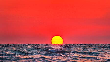 Beautiful big sunset over sea on orange sky background evening time.の写真素材