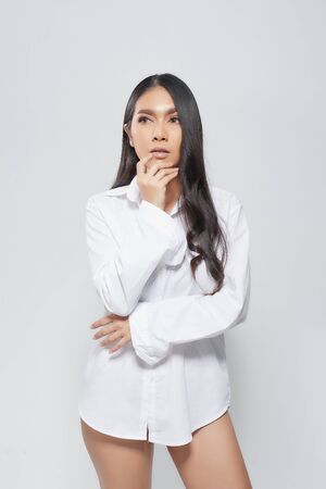 Beautiful asian woman wearing a white shirt in a sitting position on isolated gray background.の写真素材