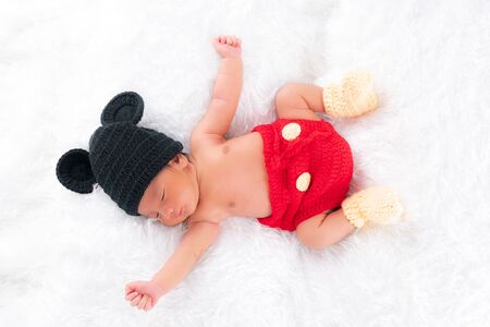 Cute little baby boy wearing a black hat wearing a cute red pants Alan is back on the white bed.の写真素材