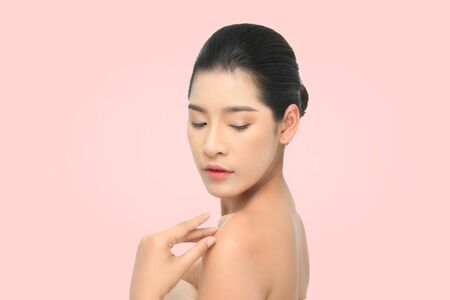 Beautiful young woman with clean fresh skin, Hair sleek, Proposing a product. Gestures for advertisement on beige background, Front view, with copy space.の写真素材
