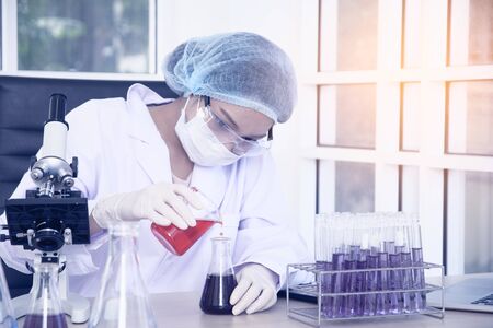 Woman scientist wearing white glue and a hair cap working with laptop, experiment at laboratory.の写真素材