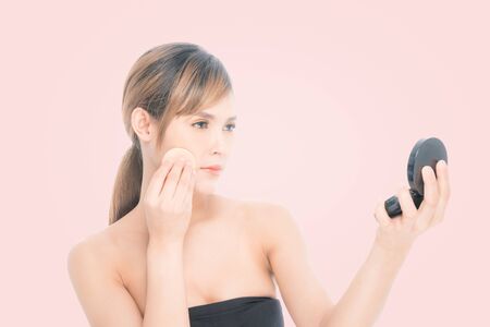 Beauty photography beautiful asian young woman with clean fresh skin, wearing black folded powder in beauty shoot studio on isolated pink background.の写真素材