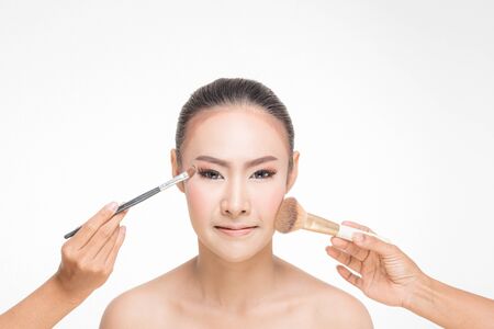 Beautiful Young Woman with clean fresh skin, Proposing a product with Makeup brush Gestures for advertisement on white backgroundの写真素材