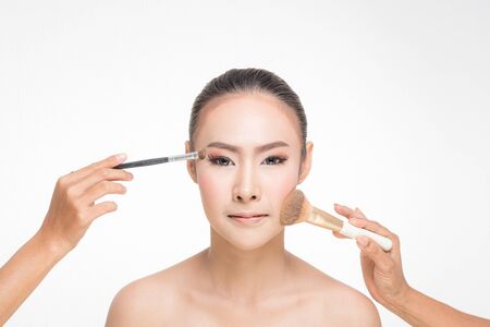 Beautiful Young Woman with clean fresh skin, Proposing a product with Makeup brush Gestures for advertisement on white backgroundの写真素材