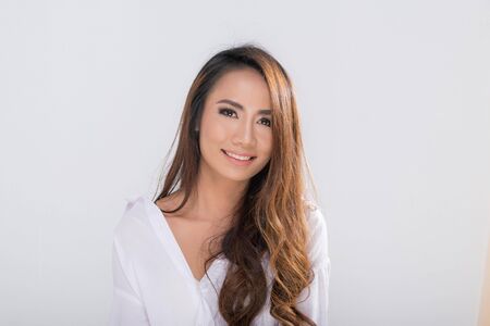 Portrait pretty smiling woman long brown hair posing wearing white shirt shooting in studio shot isolated on a white background.の写真素材