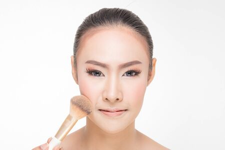 Beautiful Young Woman with clean fresh skin, Proposing a product with Makeup brush Gestures for advertisement on white backgroundの写真素材