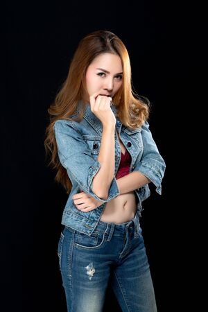 Beautiful asian woman long brown hair fashion sexy portrait wears red underwear, jeans and jacket jeans on black background.の写真素材