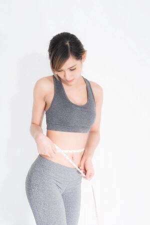 Shapely woman long hair wearing black fitness clothes in a series of exercises isolated on gray background. fitness clothes in a series of exercises now measure around her waist isolated on white background.の写真素材