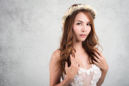 Vintage style portrait beautiful woman wearing a white dress, flower crown on gray soft blurred background.の写真素材