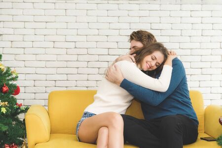 European couples, caucasian man wearing blue sweater and woman wearing white sweater, happily hugging each other in the room.の写真素材
