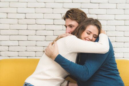 European couples, caucasian man wearing blue sweater and woman wearing white sweater, happily hugging each other in the room.の写真素材