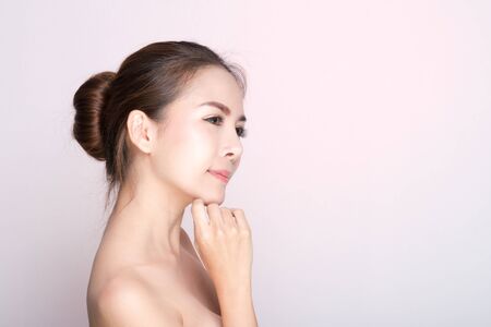 Beautiful young woman with clean fresh skin, Hair sleek, Proposing a product. Gestures for advertisement on pink background, Front view, with copy space.の写真素材