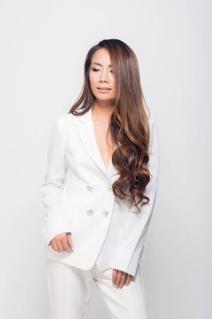 High fashion shot of beautiful portrait young woman smiling long brown hair wearing white suit show their chest at studio shoot isolated on white background.の写真素材