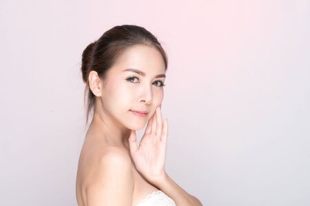 Beautiful young woman with clean fresh skin, Hair sleek, Proposing a product. Gestures for advertisement on pink background, Front view, with copy space.の写真素材
