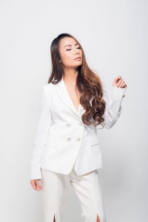 High fashion shot of beautiful portrait young woman smiling long brown hair wearing white suit show their chest at studio shoot isolated on white background.の写真素材
