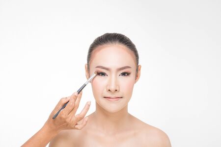 Beautiful Young Woman with clean fresh skin, Proposing a product with Makeup brush Gestures for advertisement on white backgroundの写真素材
