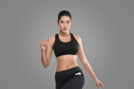 Shapely woman long hair wearing black fitness clothes in a series of exercises isolated on gray background.の写真素材