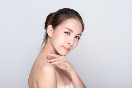 Beautiful young woman with clean fresh skin, Hair sleek, Proposing a product. Gestures for advertisement on gray background, Front view, with copy space.の写真素材