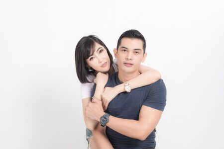 Portrait of happy young couple embracing in studio shot on white background.の写真素材