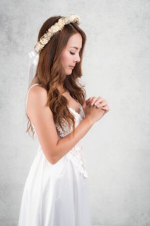 Vintage style portrait beautiful woman wearing a white dress, flower crown on gray soft blurred background.の写真素材