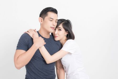 Portrait of happy young couple embracing in studio shot on white background.の写真素材