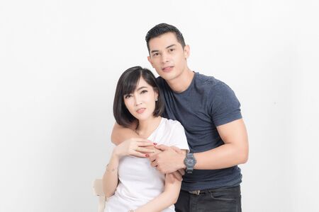 Portrait of happy young couple embracing in studio shot on white background.の写真素材
