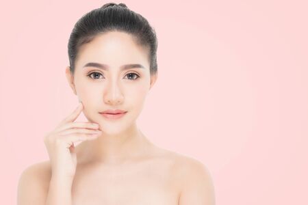 Beautiful Young Woman with clean fresh skin, Proposing a product. Gestures for advertisement on beige backgroundの写真素材