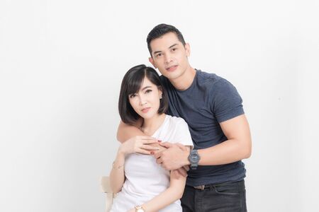 Portrait of happy young couple embracing in studio shot on white background.の写真素材