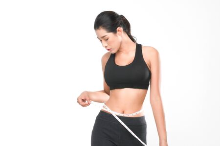 Shapely woman long hair wearing black fitness clothes in a series of exercises now measure around her waist isolated on white background.の写真素材