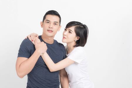 Portrait of happy young couple embracing in studio shot on white background.の写真素材