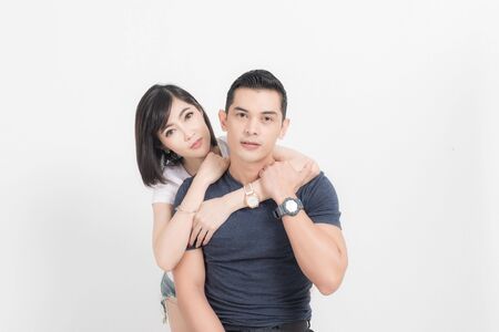 Portrait of happy young couple embracing in studio shot on white background.の写真素材