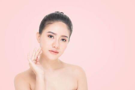 Beautiful Young Woman with clean fresh skin, Proposing a product. Gestures for advertisement on beige backgroundの写真素材