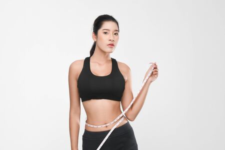 Shapely woman long hair wearing black fitness clothes in a series of exercises now measure around her waist isolated on white background.の写真素材