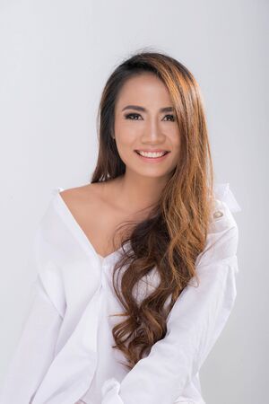 Portrait pretty smiling woman long brown hair posing wearing white shirt shooting in studio shot isolated on a white background.の写真素材