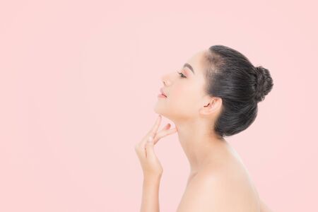 Beautiful Young Woman with clean fresh skin, Proposing a product. Gestures for advertisement on beige backgroundの写真素材